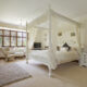 Traditional Bedroom Design with a white four-post bed in large neutral-colored bedroom