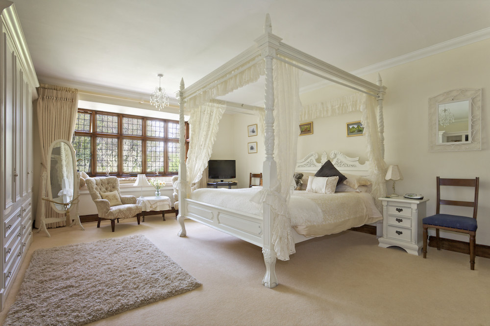 Traditional Bedroom Design with a white four-post bed in large neutral-colored bedroom