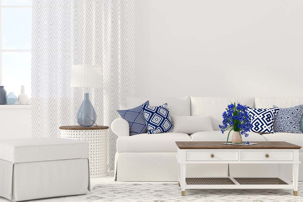 Beachy and Nautical Interior Design with white walls, white couch, white coffee table with wood accents and royal blue throw pillows